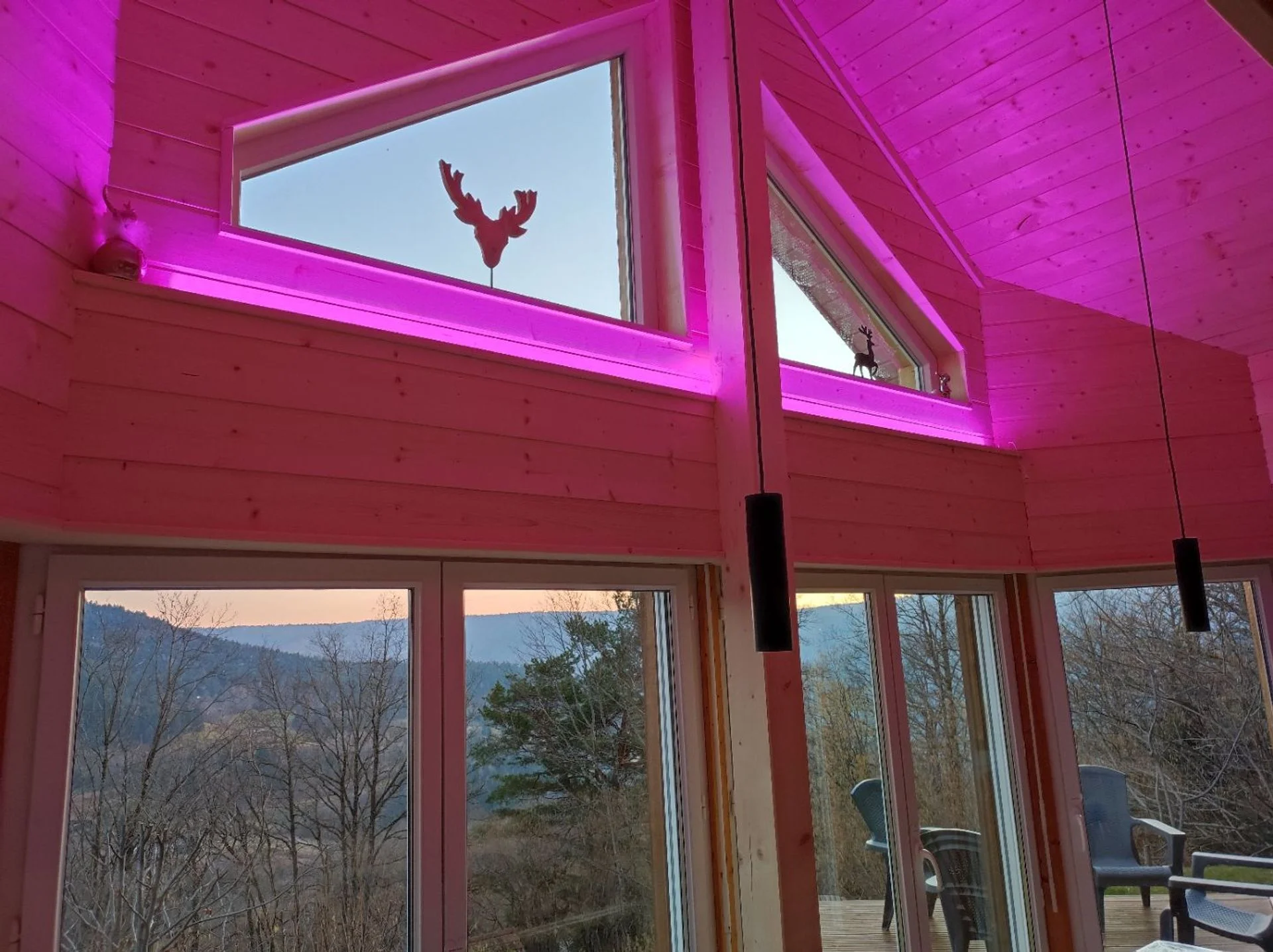 Intérieur du chalet avec lumières LED roses et vue sur la vallée